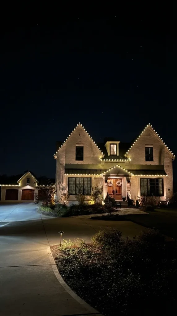 Vertical view of a home with warm white roofline Christmas lights at night